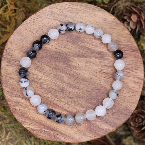 Ce bracelet en perles de quartz tourmaline est soigneusement confectionné à partir de perles authentiques, offrant non seulement un bijou esthétique, mais aussi un outil spirituel puissant. Le quartz tourmaline agit principalement sur les chakras racine et plexus solaire, deux centres énergétiques essentiels pour se sentir ancré et en harmonie avec soi-même.