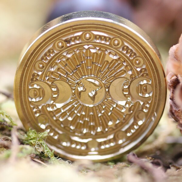 Ce tampon de cire à cacheter évoque à la fois la beauté du geste ancien et la symbolique mystique des cycles lunaires. Doté d’un manche en bois brun rouge au fini vieilli, il dégage une chaleur naturelle et une authenticité rare. L’embout, en métal doré patiné, représente les phases de la lune dans un enchaînement délicat et parfaitement gravé.
