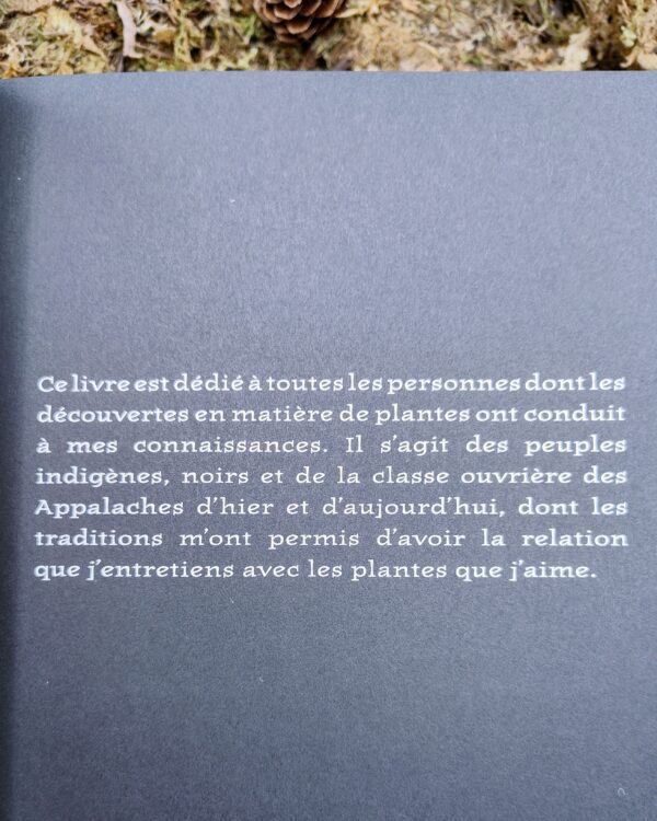 Un carnet de notes ouvert à côté de ciseaux de jardinage, d’un mortier et de fioles d’herbes séchées